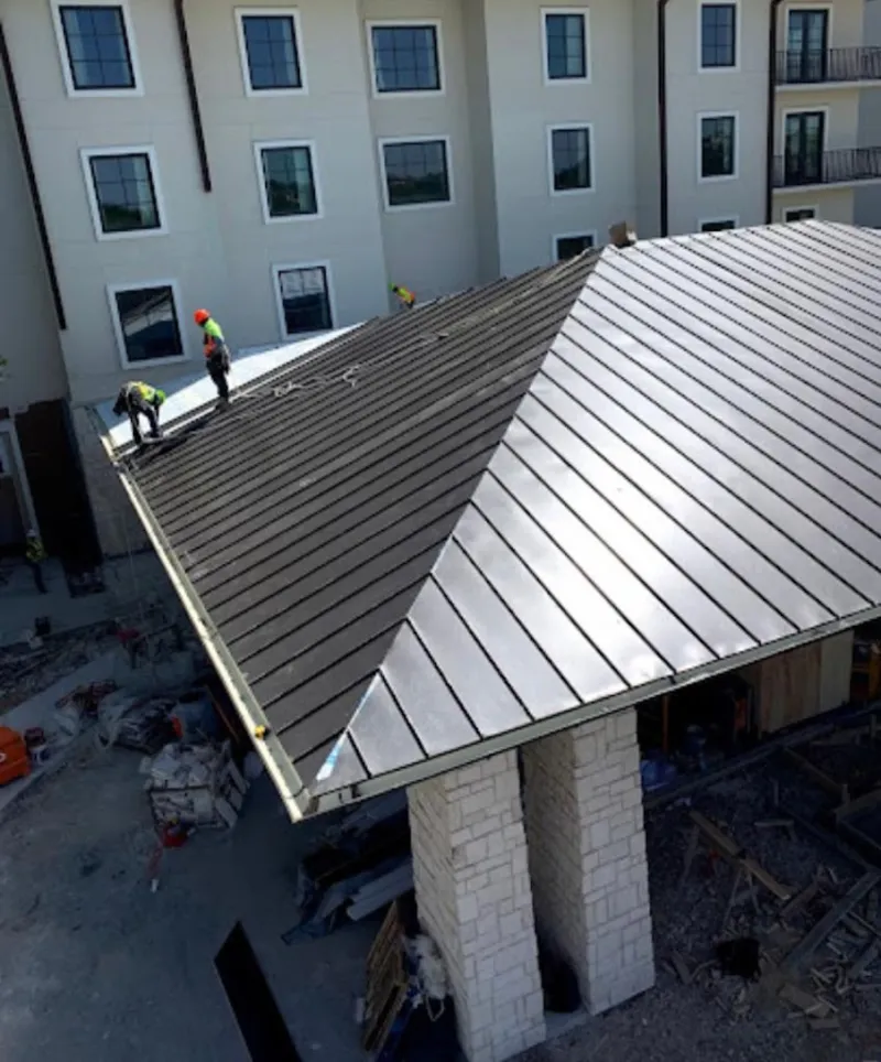 Crew installing standing seam metal roof panels on a commercial project in Moore